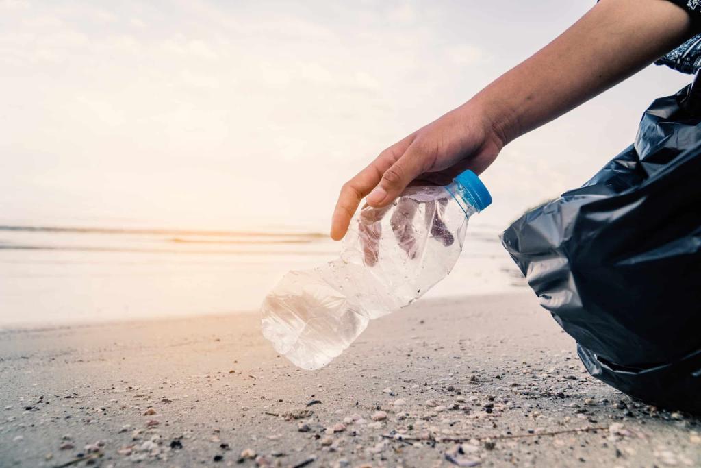 Mikroplastik im Trinkwasser: Mann sammelt mit schwarzem Beutel Plastikflaschen vom Strand auf