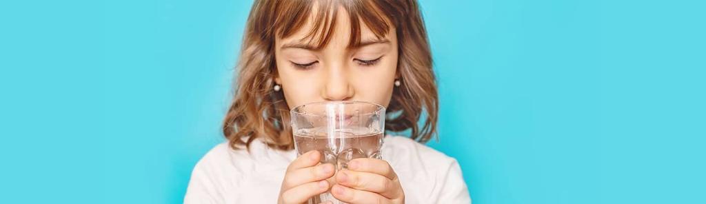 junges Mädchen mit braunen Haaren hält Glas Wasser